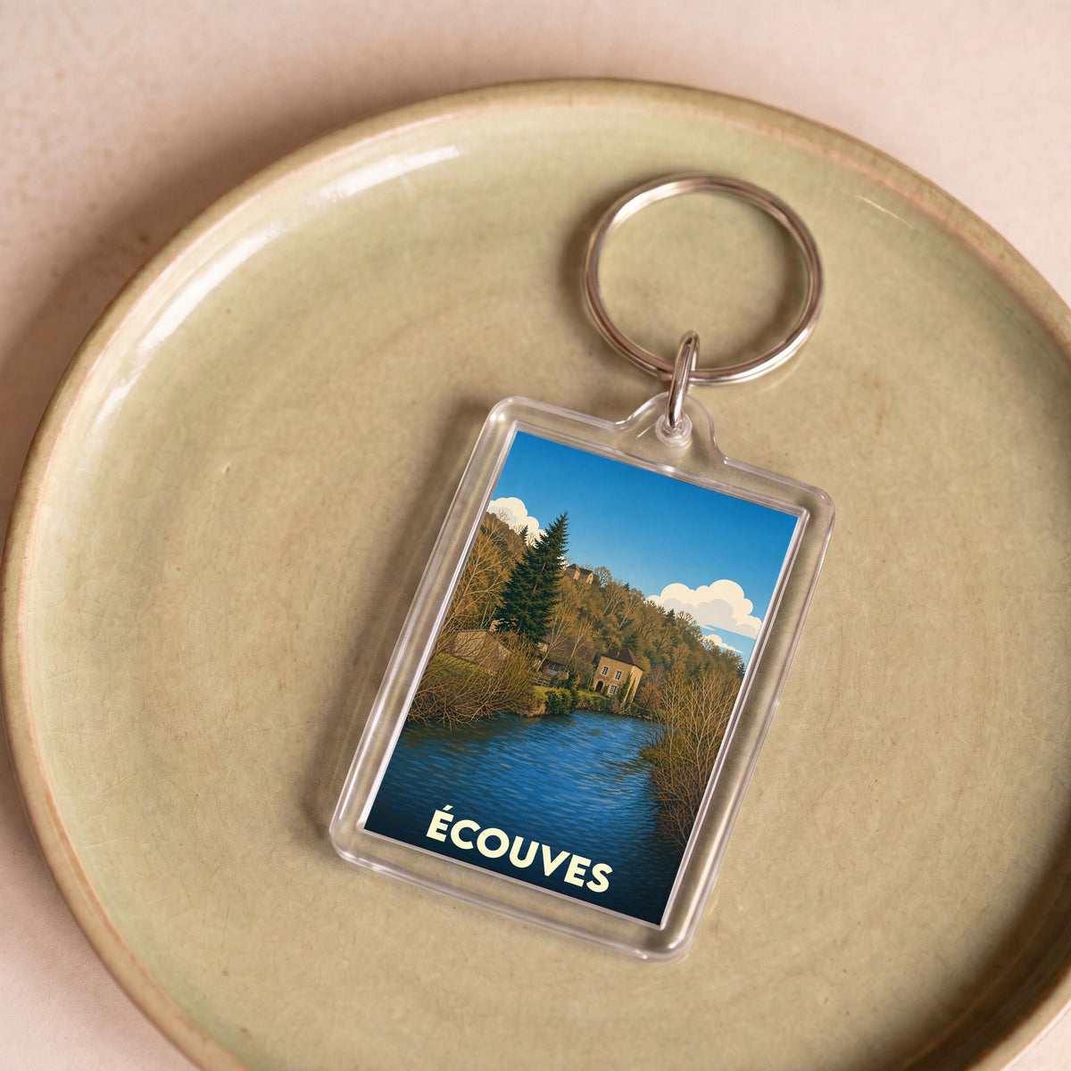 Porte-clés souvenir de la commune d'Écouves avec une illustration stylisée d'un paysage fluvial.