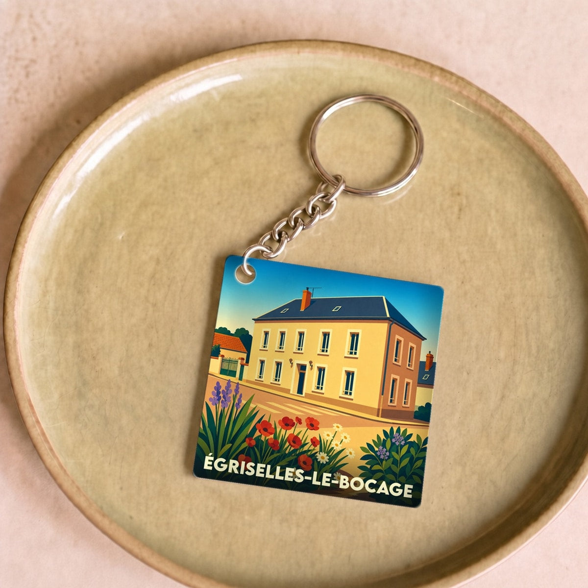 Porte-clés souvenir de la ville d'Égriselles-le-Bocage avec une illustration stylisée d'une maison de village.