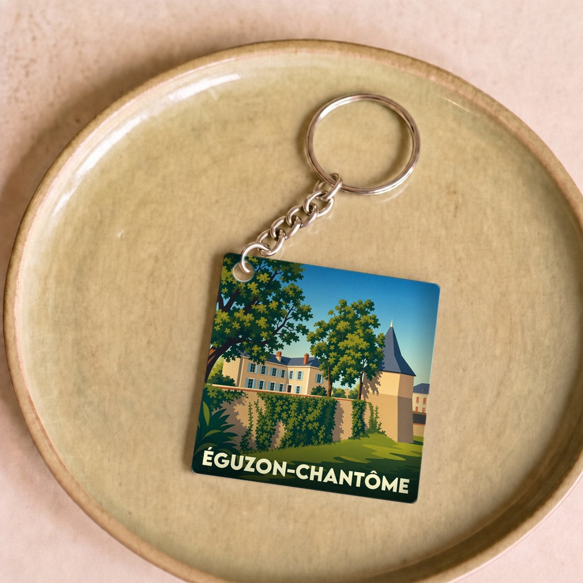 Porte-clés souvenir de la ville d'Éguzon-Chantôme avec une illustration stylisée.
