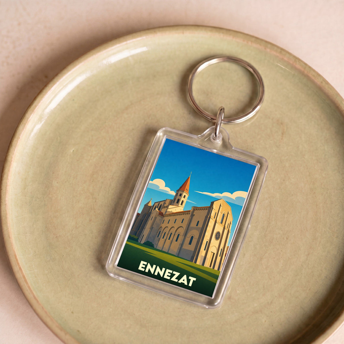 Porte-clés souvenir de la ville d'Ennezat avec une illustration stylisée de sa collégiale.