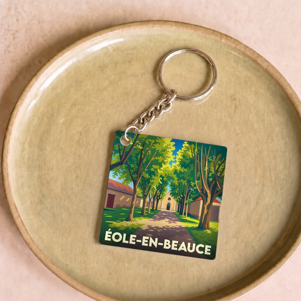 Porte-clés souvenir de la commune d'Éole-en-Beauce avec une illustration stylisée d'une allée arborée.
