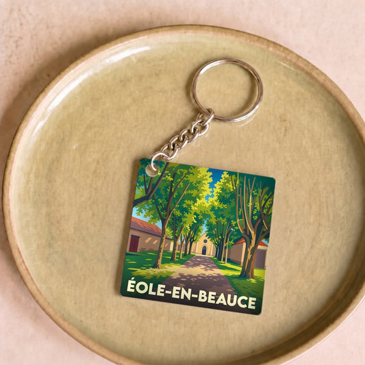 Porte-clés souvenir de la commune d'Éole-en-Beauce avec une illustration stylisée d'une allée arborée.