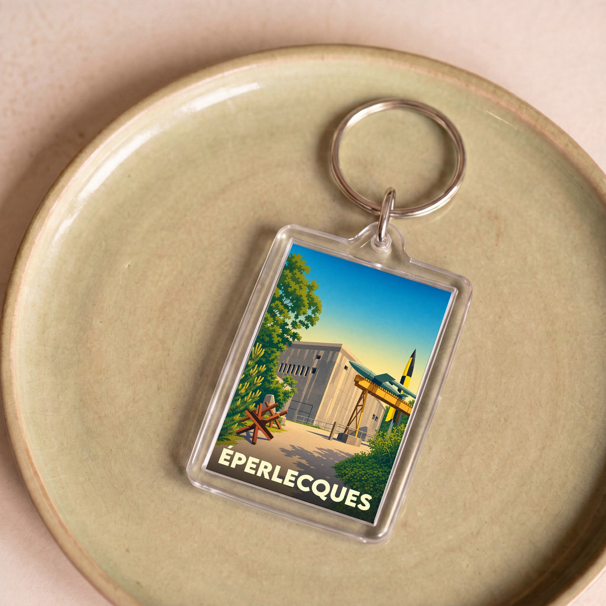 Porte-clés souvenir de la ville d'Éperlecques avec une illustration stylisée d'un blockhaus et de fusées.