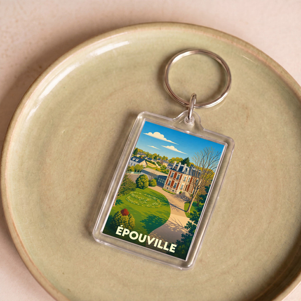 Porte-clés souvenir de la ville d'Épouville avec une illustration stylisée d'un manoir et son parc.
