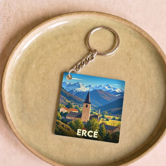 Porte-clés souvenir de la ville de Ercé avec une illustration stylisée de son église face aux montagnes.