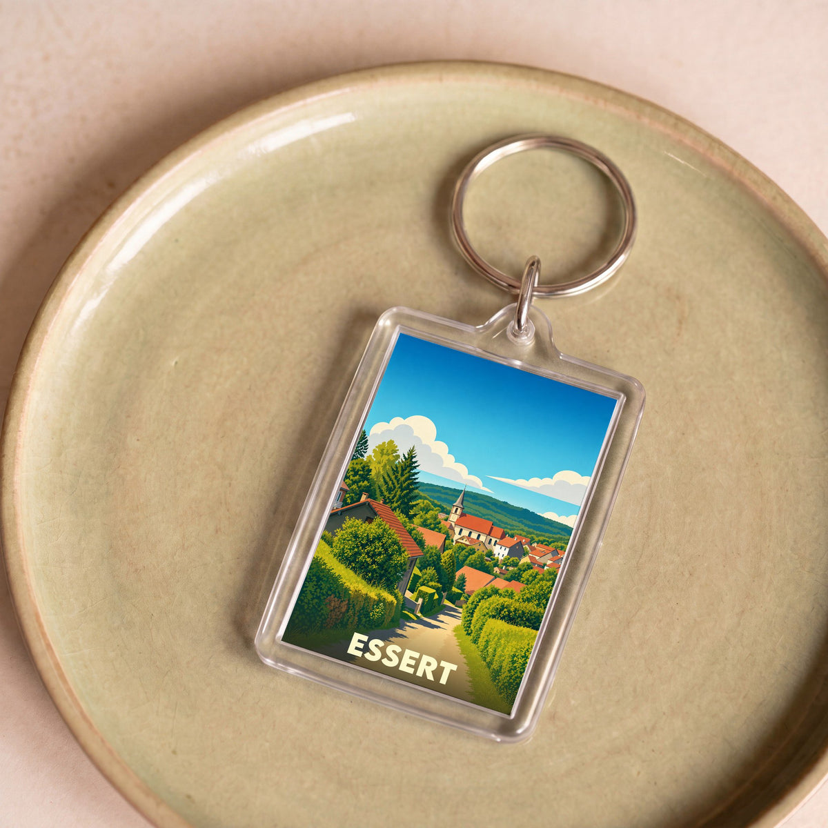 Porte-clés souvenir de la ville d'Essert avec une illustration stylisée d'un village verdoyant.