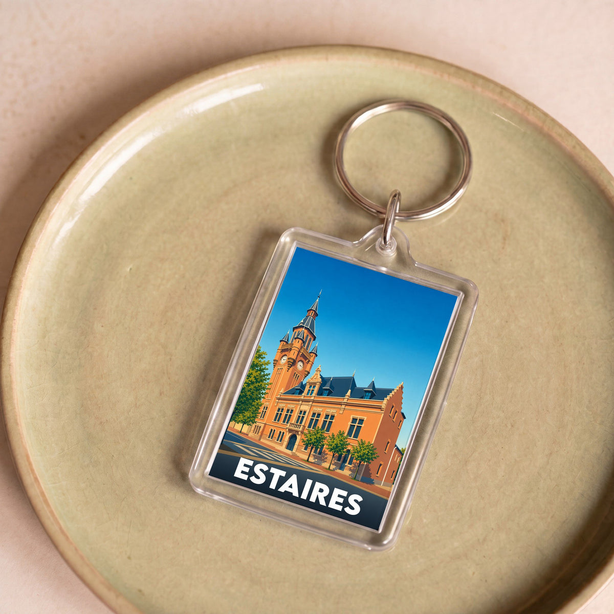 Porte-clés souvenir de la ville d'Estaires avec une illustration stylisée de son hôtel de ville.