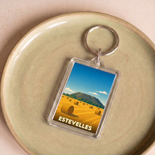 Porte-clés souvenir de la ville d'Estevelles avec une illustration stylisée d'un champ de foin.