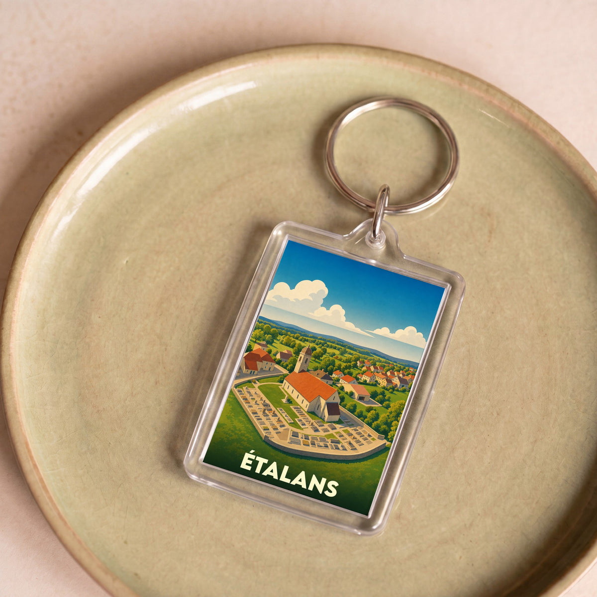 Porte-clés souvenir de la ville d'Étalans avec une illustration stylisée.