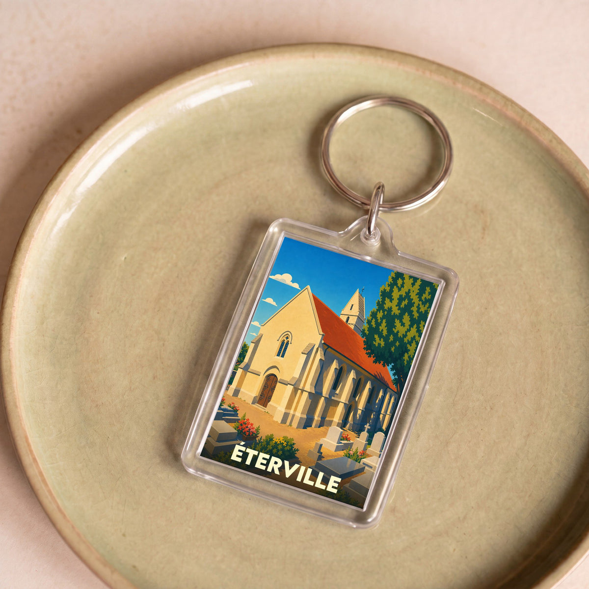 Porte-clés souvenir de la ville de Éterville avec une illustration stylisée de son église.