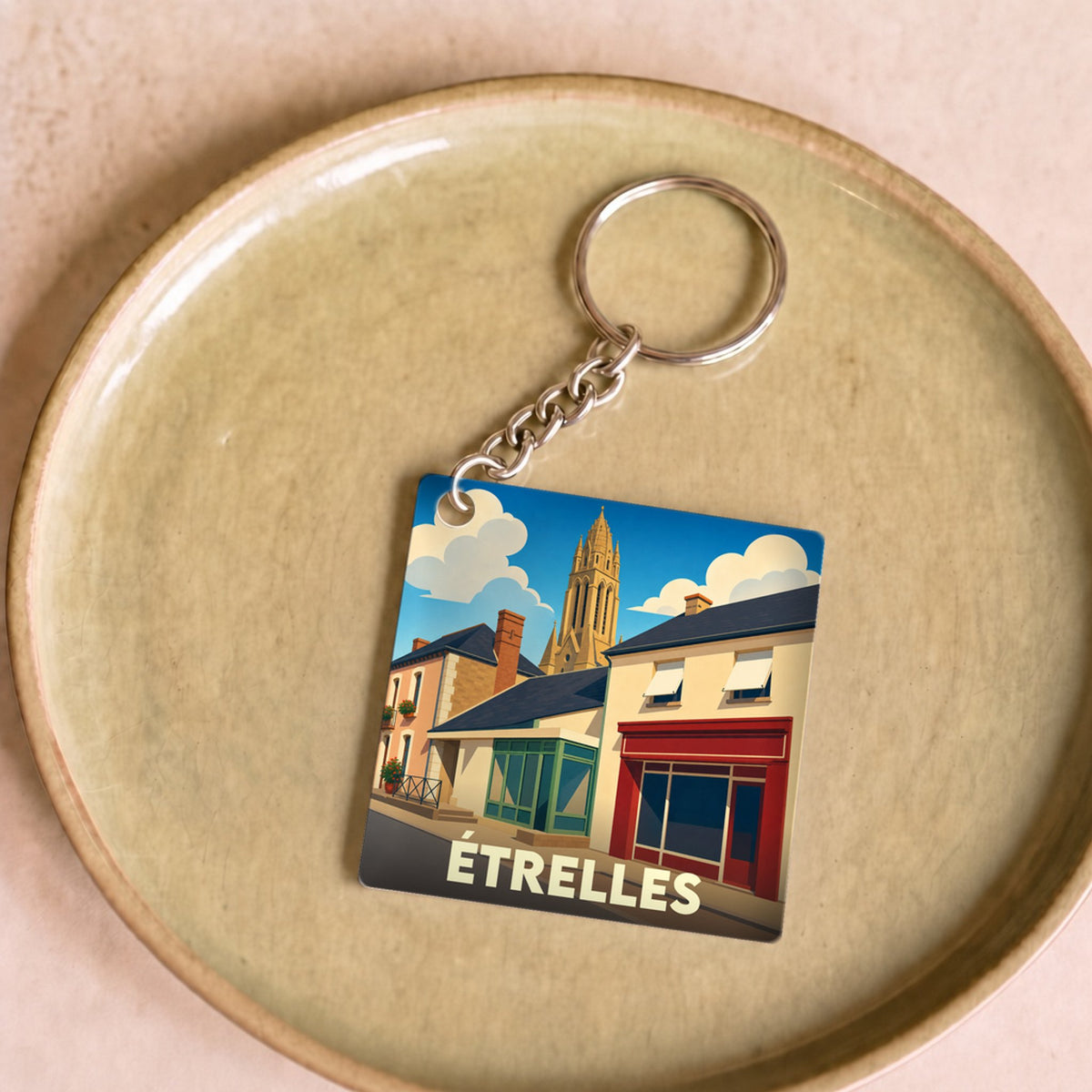 Porte-clés souvenir de la ville d'Étrelles avec une illustration stylisée.