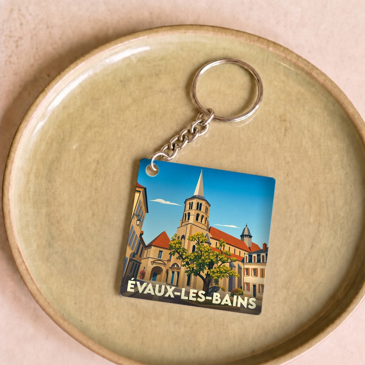 Porte-clés souvenir de la ville d'Évaux-les-Bains avec une illustration stylisée de son patrimoine architectural.