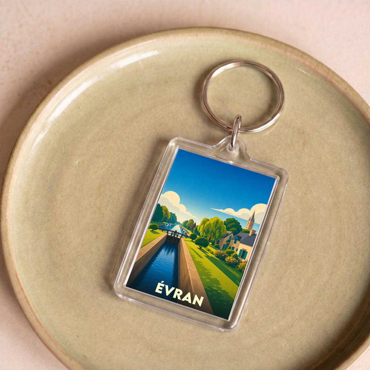Porte-clés souvenir de la ville de Évran avec une illustration stylisée d'un canal et d'une écluse.