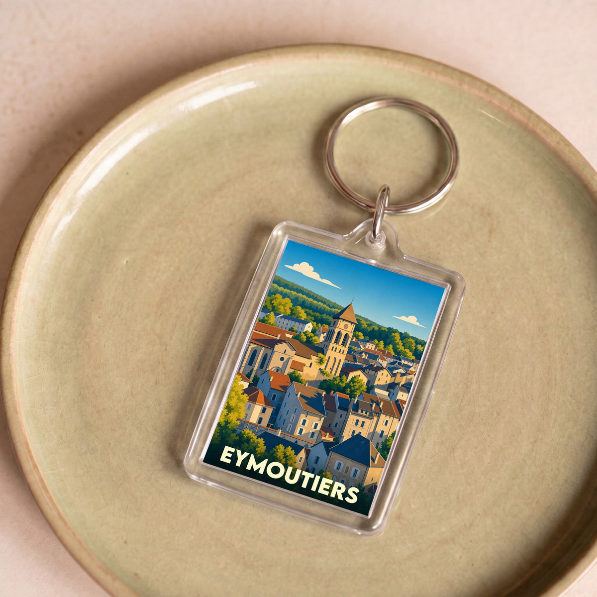 Porte-clés souvenir de la ville d'Eymoutiers avec une illustration stylisée.