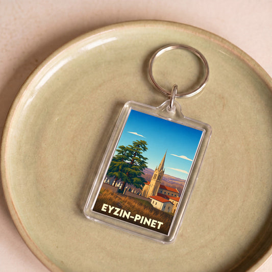 Porte-clés souvenir de la ville d'Eyzin-Pinet avec une illustration stylisée de son église et de son paysage.