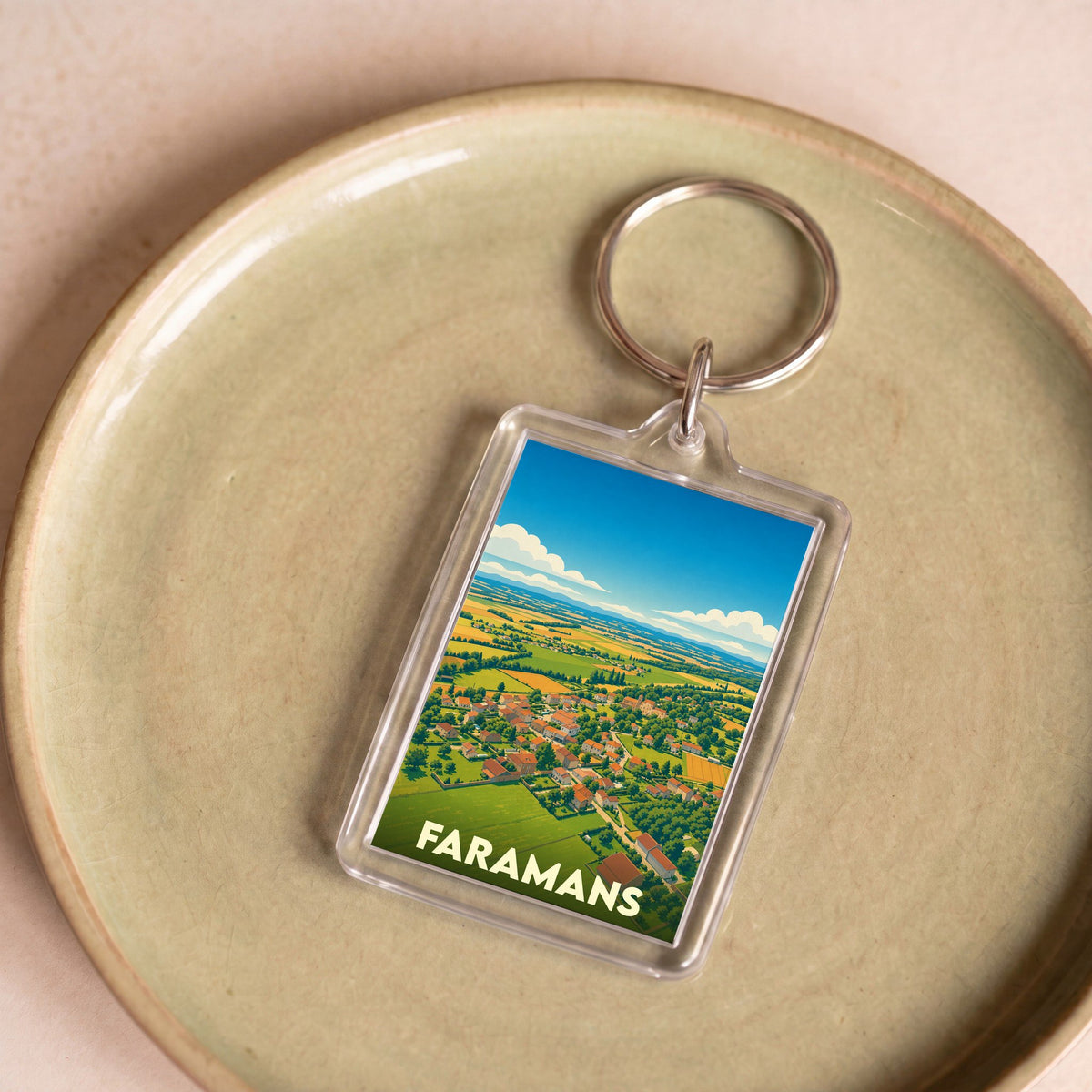 Porte-clés souvenir de la ville de Faramans avec une illustration stylisée de son paysage.