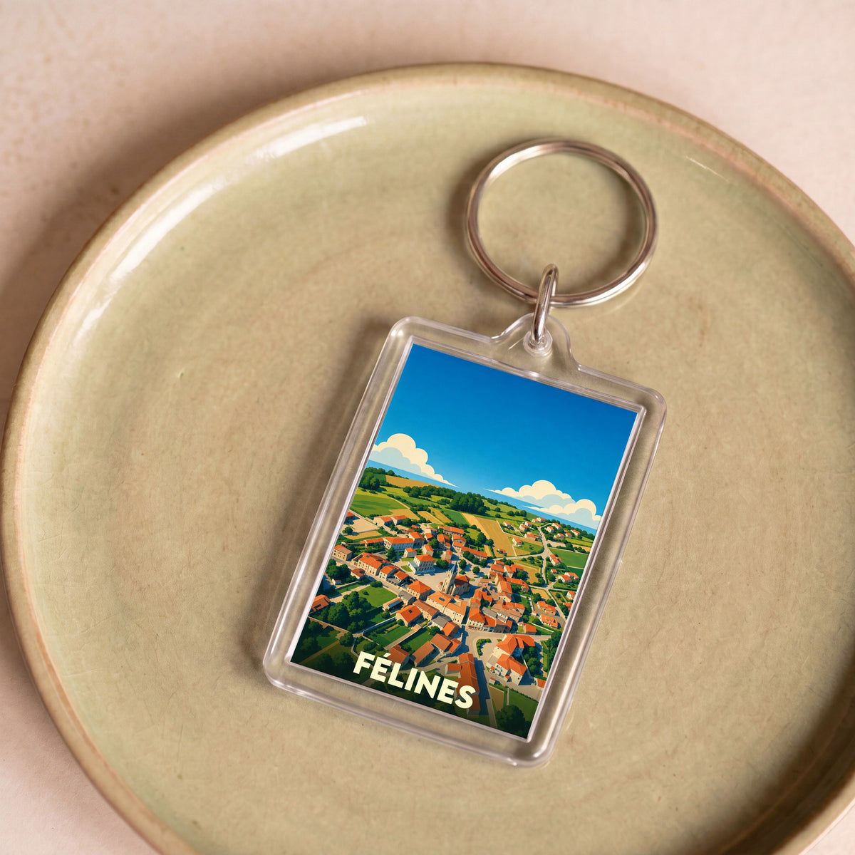 Porte-clés souvenir de la ville de Félines avec une illustration stylisée d'une vue aérienne du village.