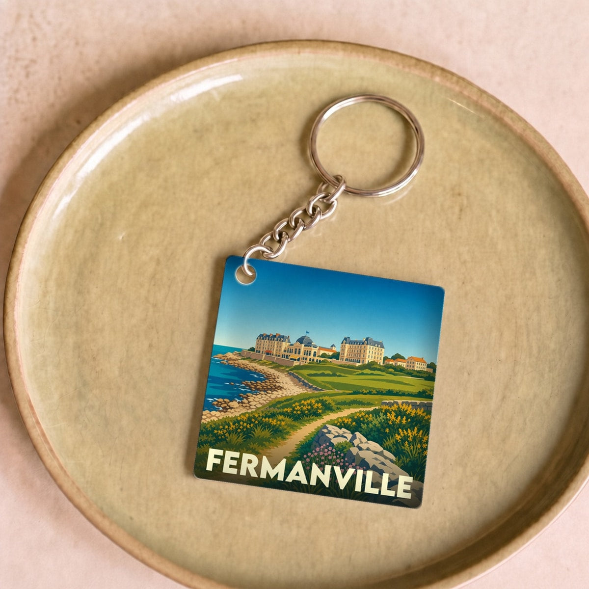 Porte-clés souvenir de la ville de Fermanville avec une illustration stylisée du littoral et du patrimoine local.