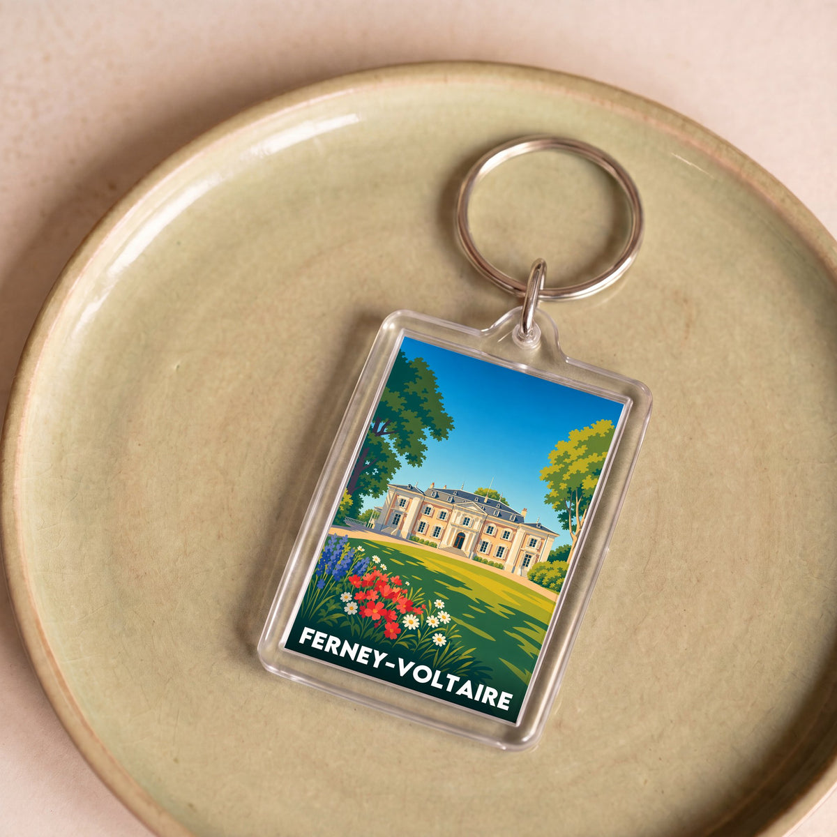 Porte-clés souvenir de la ville de Ferney-Voltaire avec une illustration stylisée.