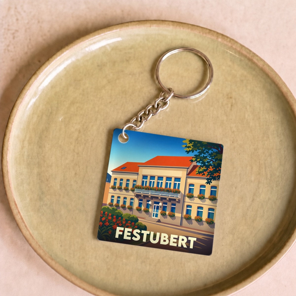 Porte-clés souvenir de la ville de Festubert avec une illustration stylisée d'un bâtiment fleuri.