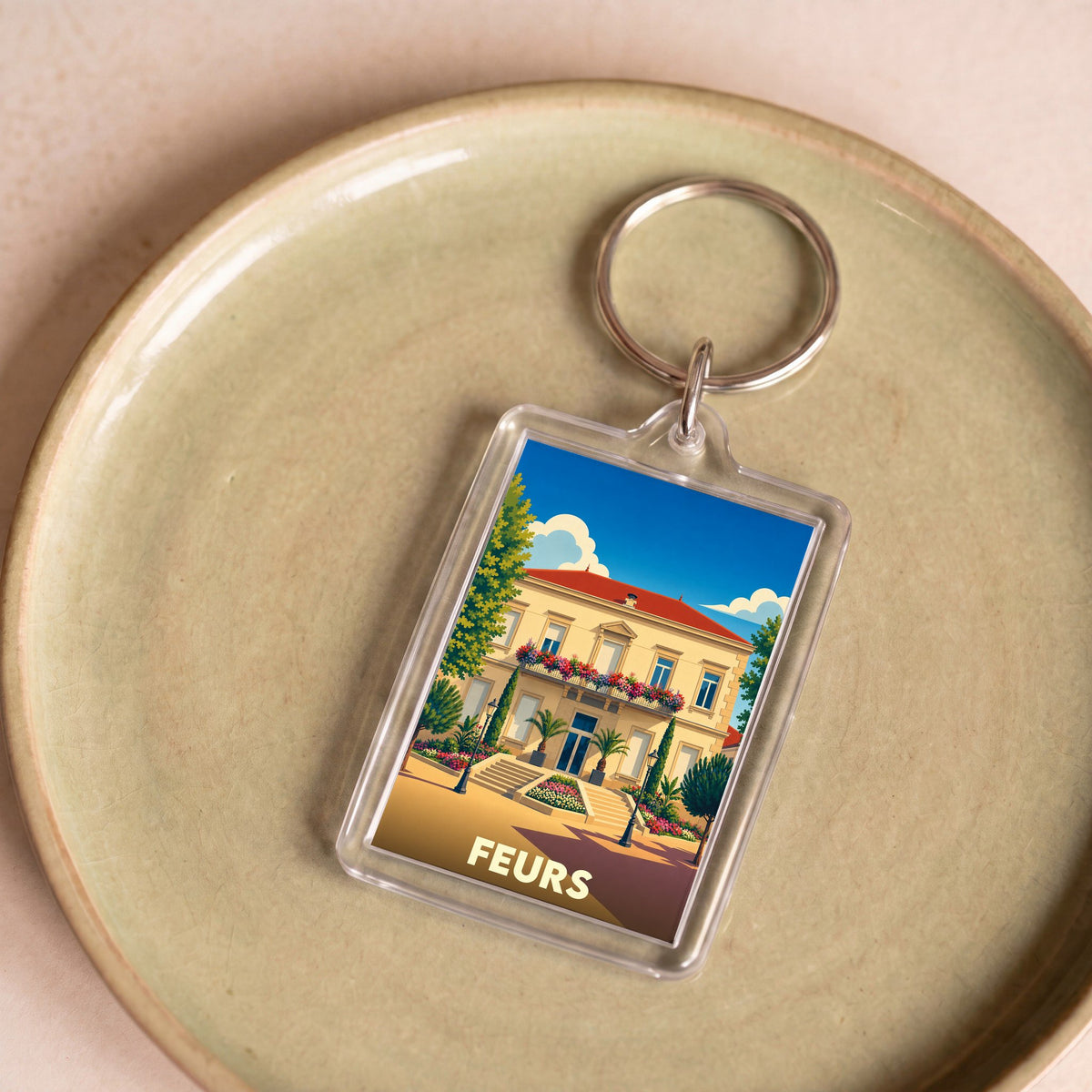 Porte-clés souvenir de la ville de Feurs avec une illustration stylisée.