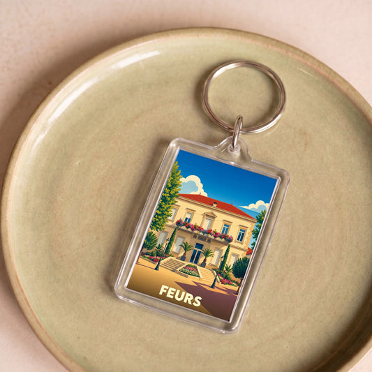 Porte-clés souvenir de la ville de Feurs avec une illustration stylisée.