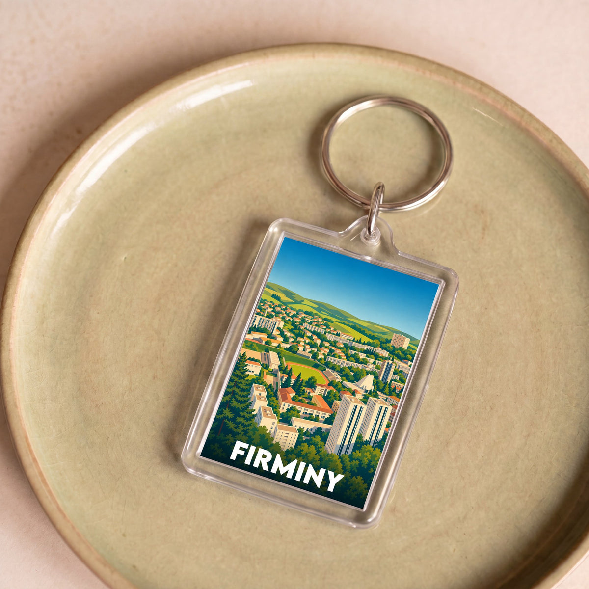 Porte-clés souvenir de la ville de Firminy avec une illustration stylisée du paysage urbain.