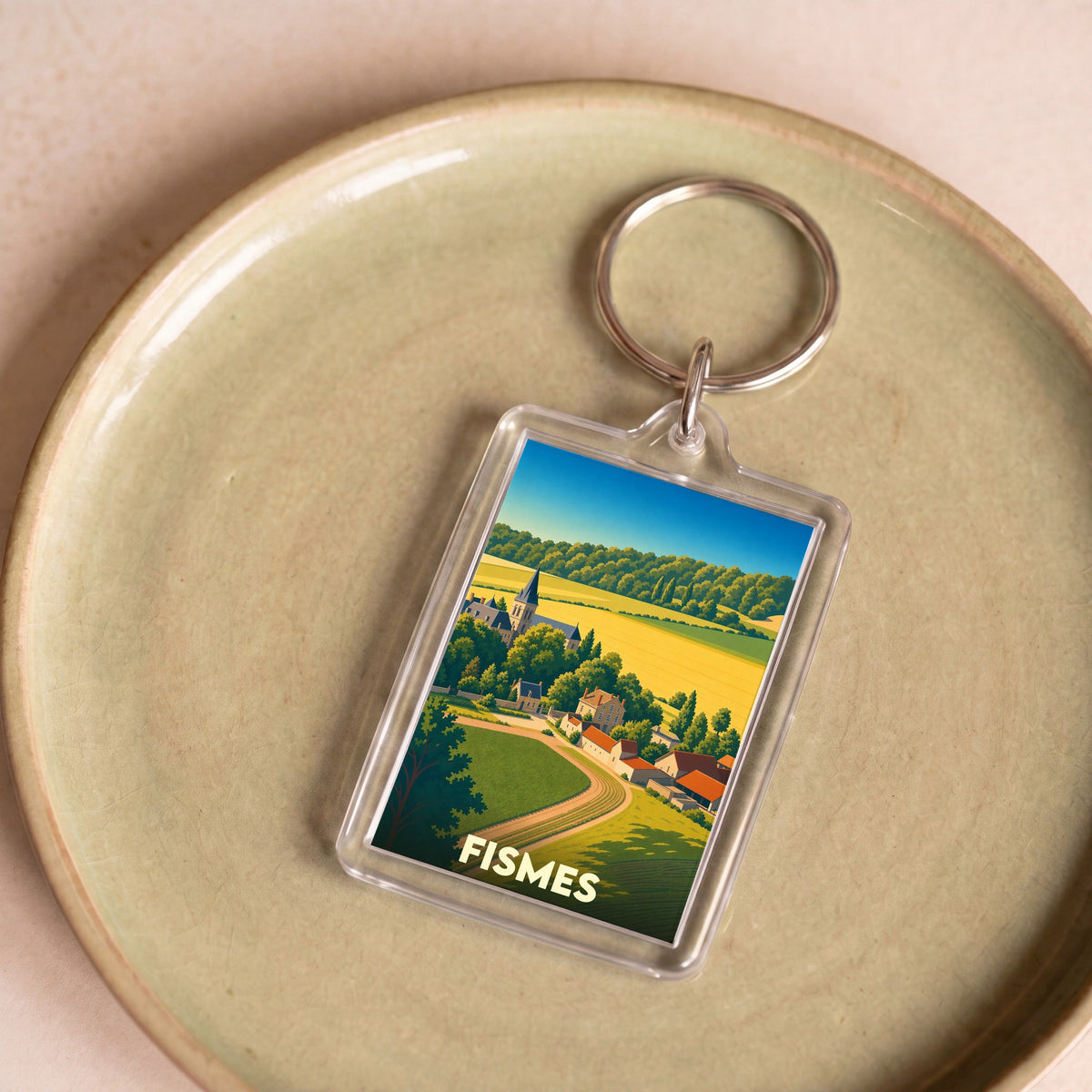 Porte-clés souvenir de la ville de Fismes avec une illustration stylisée de son paysage champêtre.