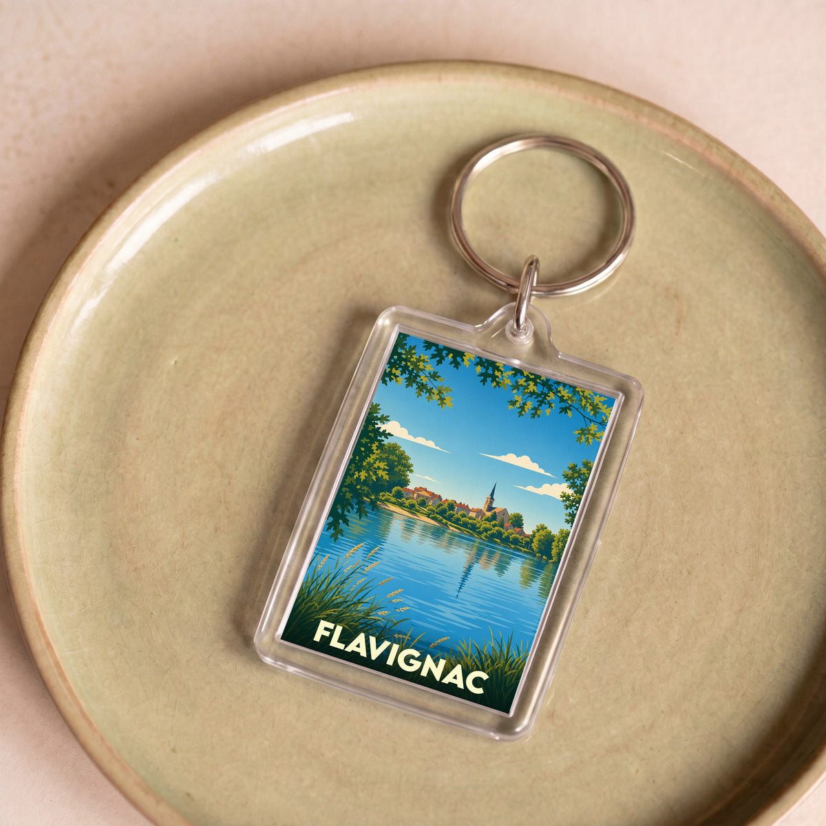 Porte-clés souvenir de la ville de Flavignac avec une illustration stylisée d'un paysage lacustre.