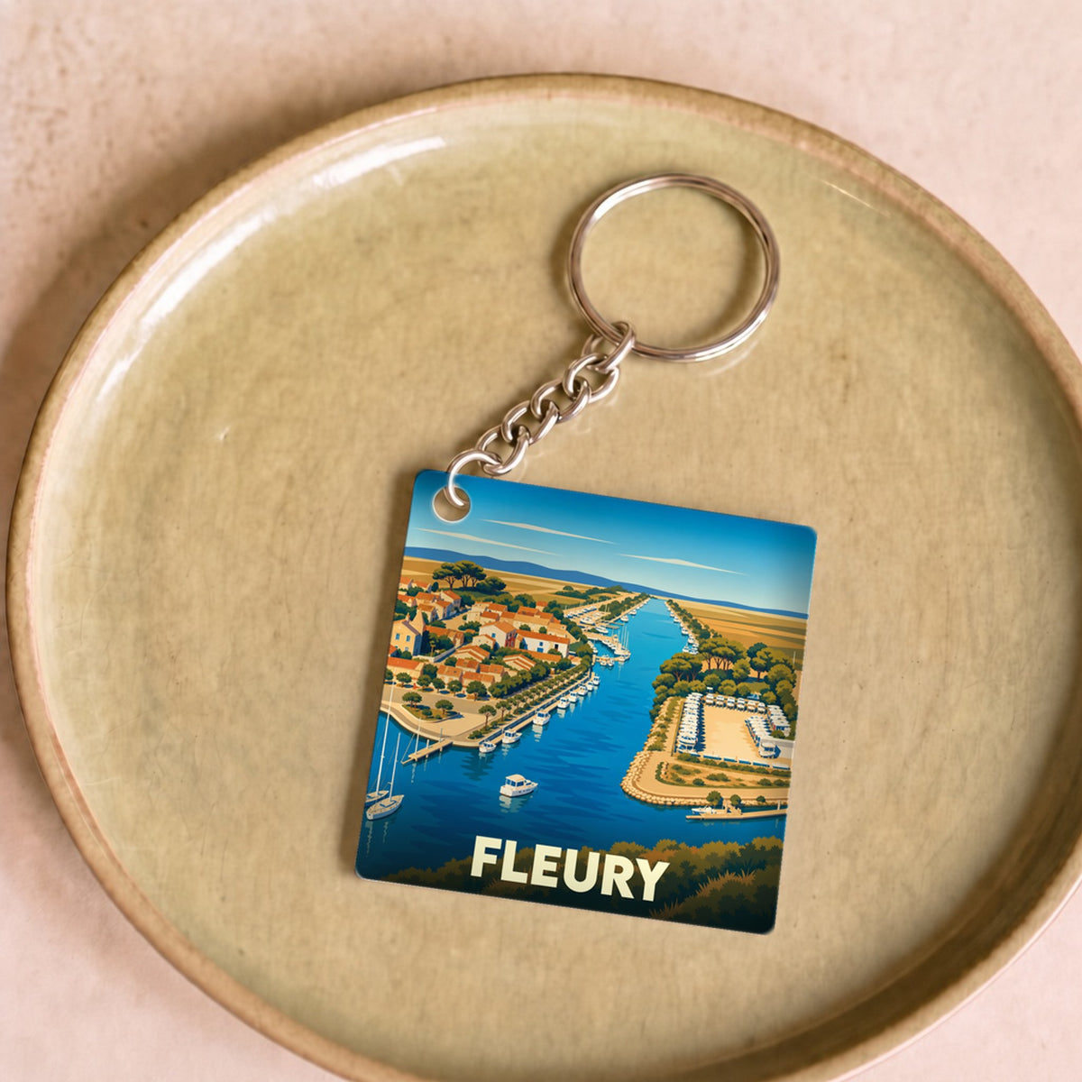 Porte-clés souvenir de la ville de Fleury avec une illustration stylisée de son port.