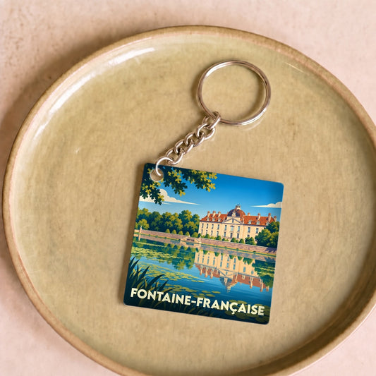 Porte-clés souvenir de la ville de Fontaine-Française avec une illustration stylisée de son château se reflétant dans l'eau.