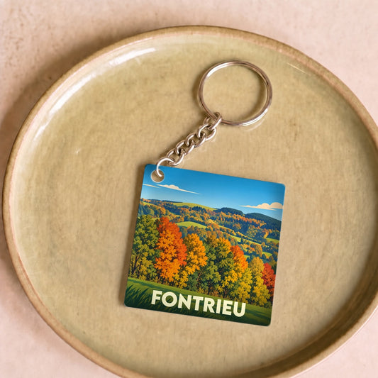 Porte-clés souvenir de la ville de Fontrieu avec une illustration automnale de paysages vallonnés.