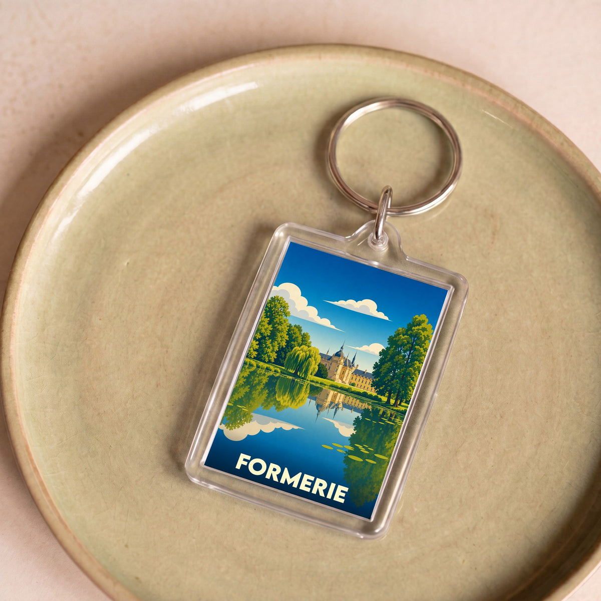 Porte-clés souvenir de la ville de Formerie avec une illustration stylisée d'un château se reflétant dans l'eau.
