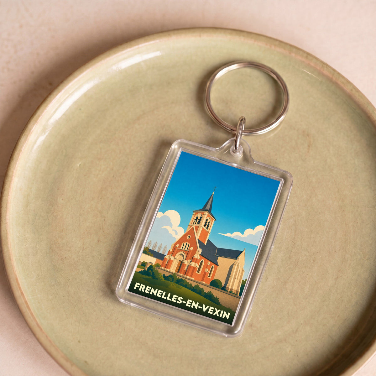 Porte-clés souvenir de la ville de Frenelles-en-Vexin avec une illustration stylisée de son église.
