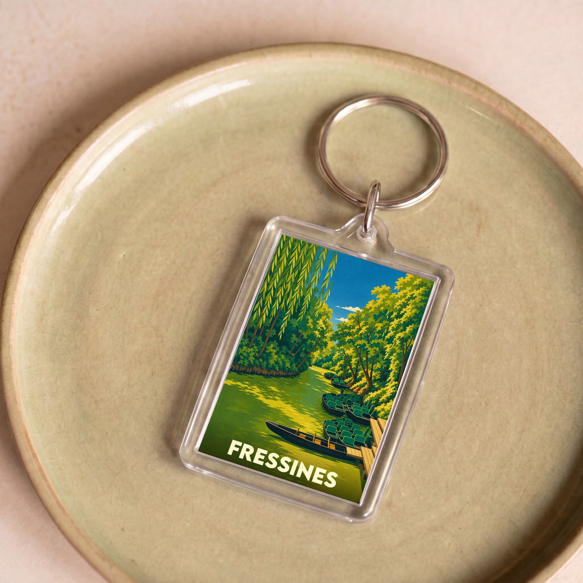 Porte-clés souvenir de la ville de Fressines avec une illustration stylisée d'un canal boisé.