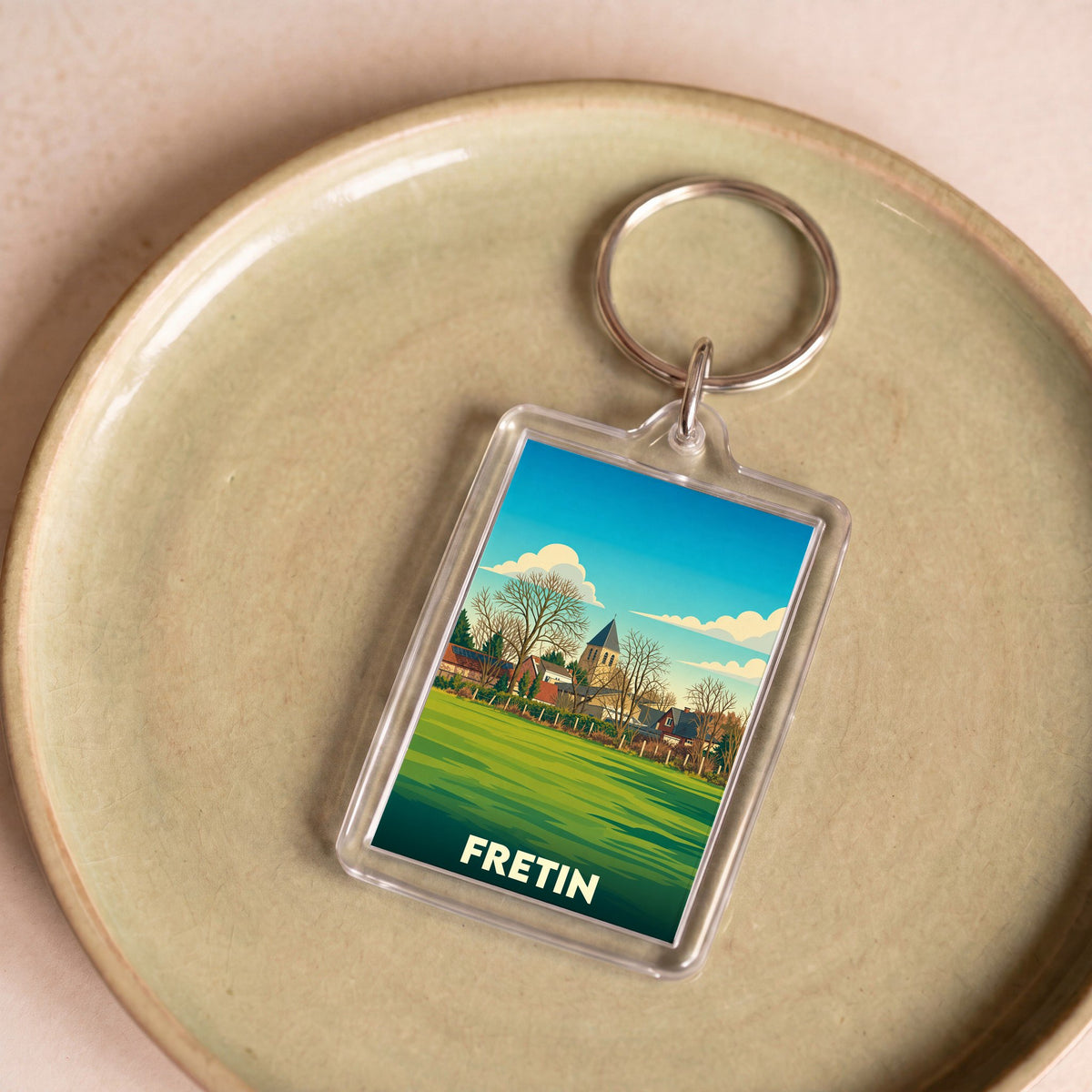 Porte-clés souvenir de la ville de Fretin avec une illustration stylisée.
