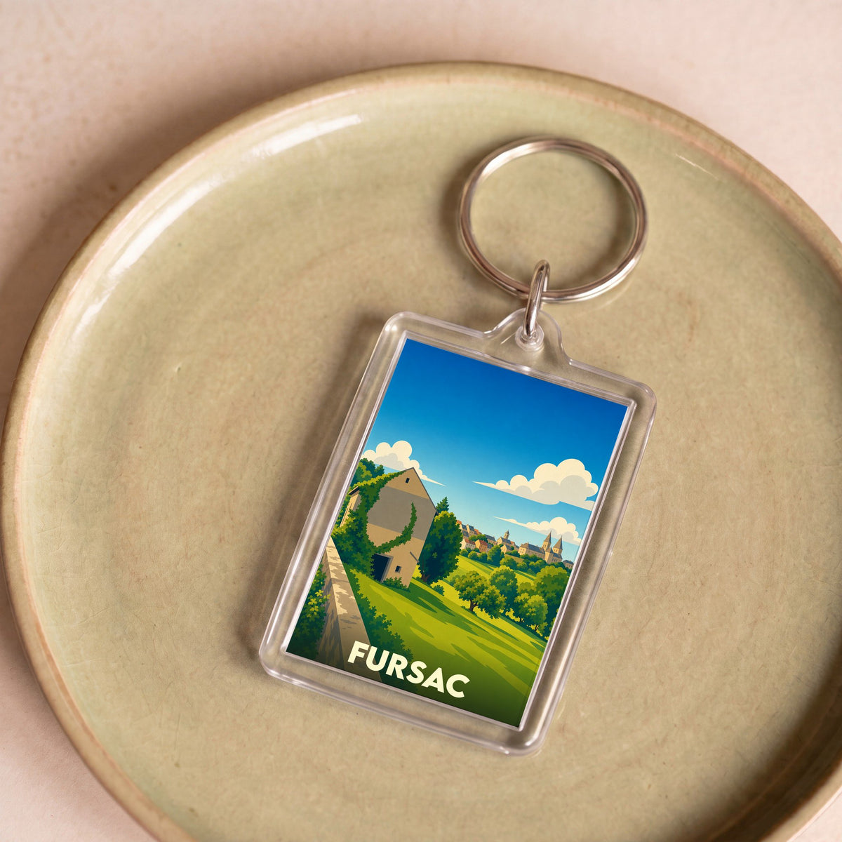 Porte-clés souvenir de la ville de Fursac avec une illustration stylisée de son paysage champêtre.