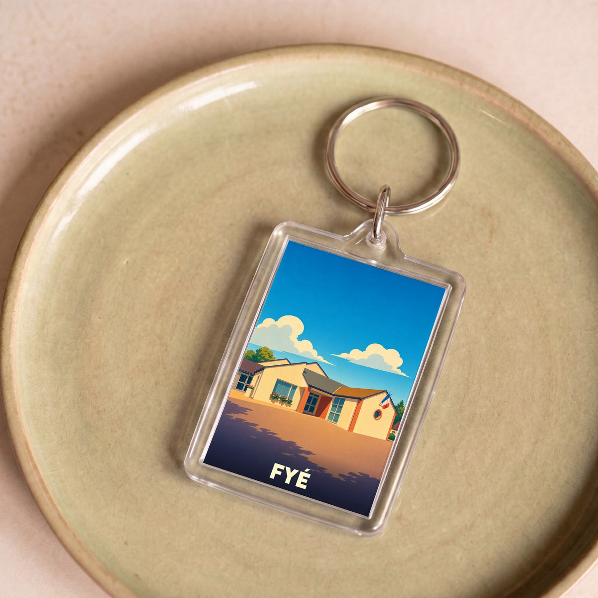 Porte-clés souvenir de la ville de Fyé avec une illustration stylisée d'un bâtiment sous un ciel bleu.