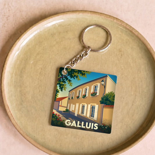 Porte-clés souvenir de la ville de Galluis avec une illustration stylisée d'une rue ensoleillée.