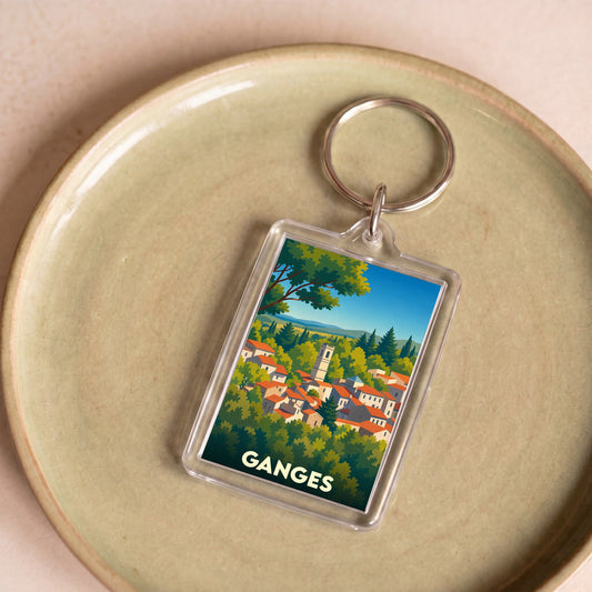 Porte-clés souvenir de la ville de Ganges avec une illustration stylisée d'un village pittoresque.