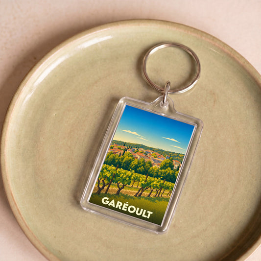 Porte-clés souvenir de la ville de Garéoult illustré d'un paysage de vignobles provençaux.
