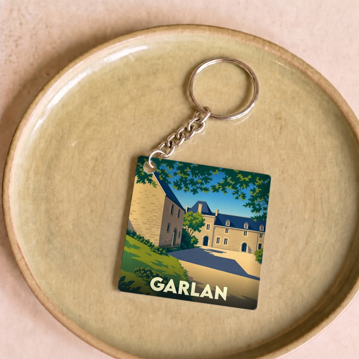 Porte-clés souvenir de la ville de Garlan avec une illustration stylisée d'un manoir breton.