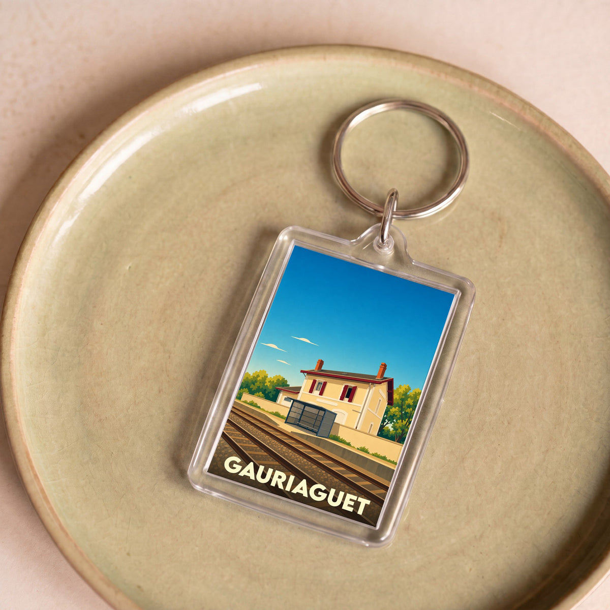Porte-clés souvenir de la ville de Gauriaguet avec une illustration stylisée d'une gare.