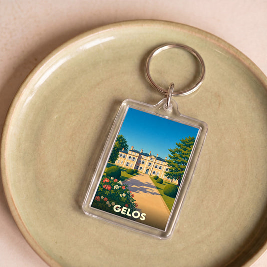 Porte-clés souvenir de la ville de Gelos avec une illustration stylisée d'un domaine historique.