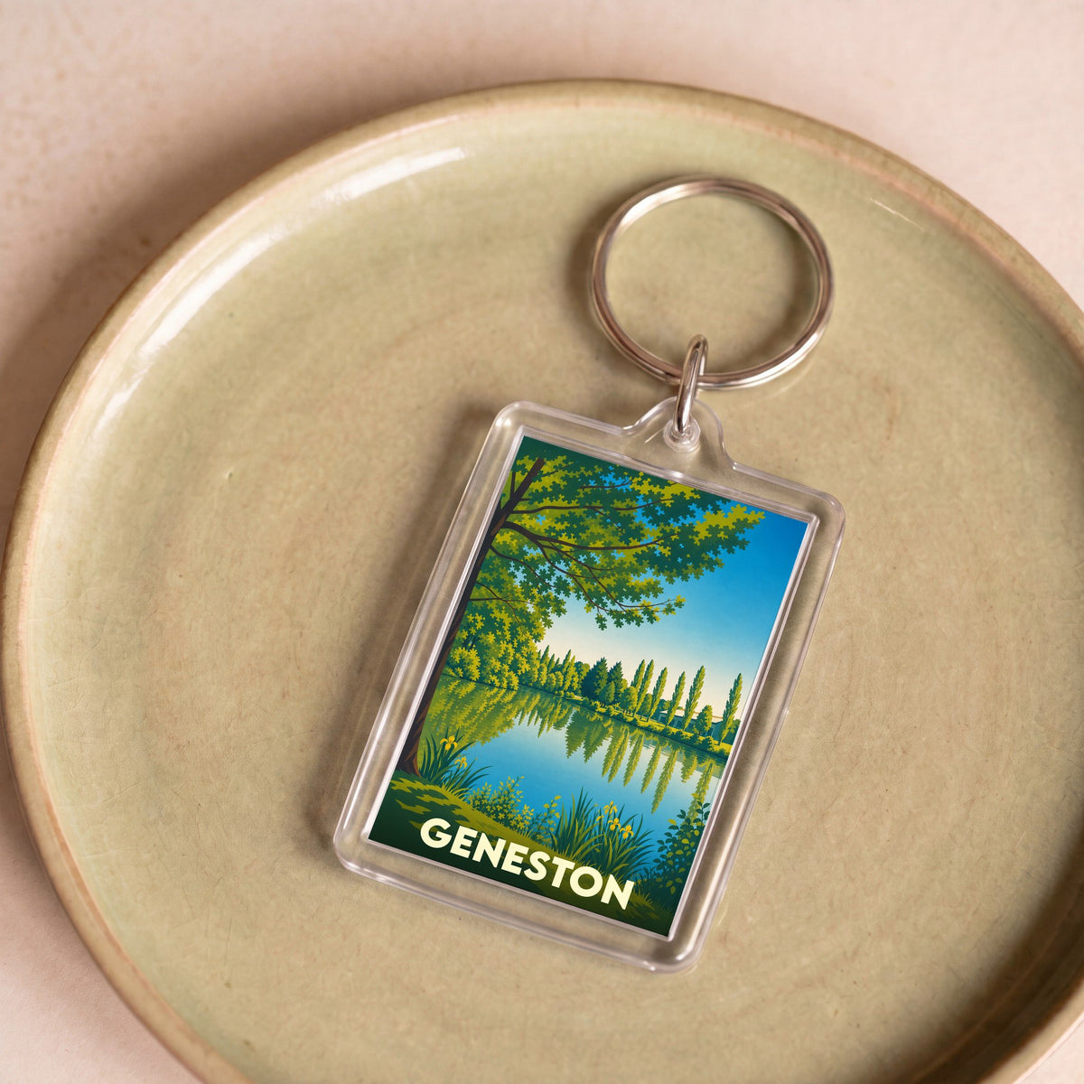 Porte-clés souvenir de la ville de Geneston avec une illustration stylisée d'un lac bordé d'arbres.