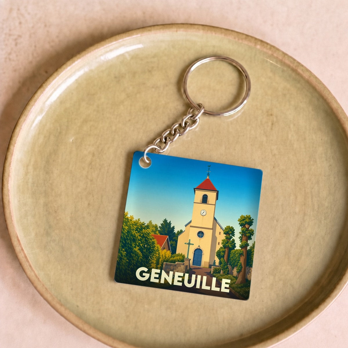 Porte-clés souvenir de la ville de Geneuille avec une illustration stylisée de son église.