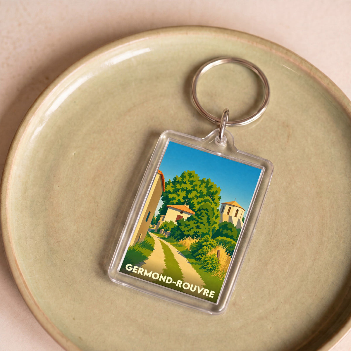 Porte-clés souvenir de la ville de Germond-Rouvre avec une illustration stylisée d'un paysage de village.