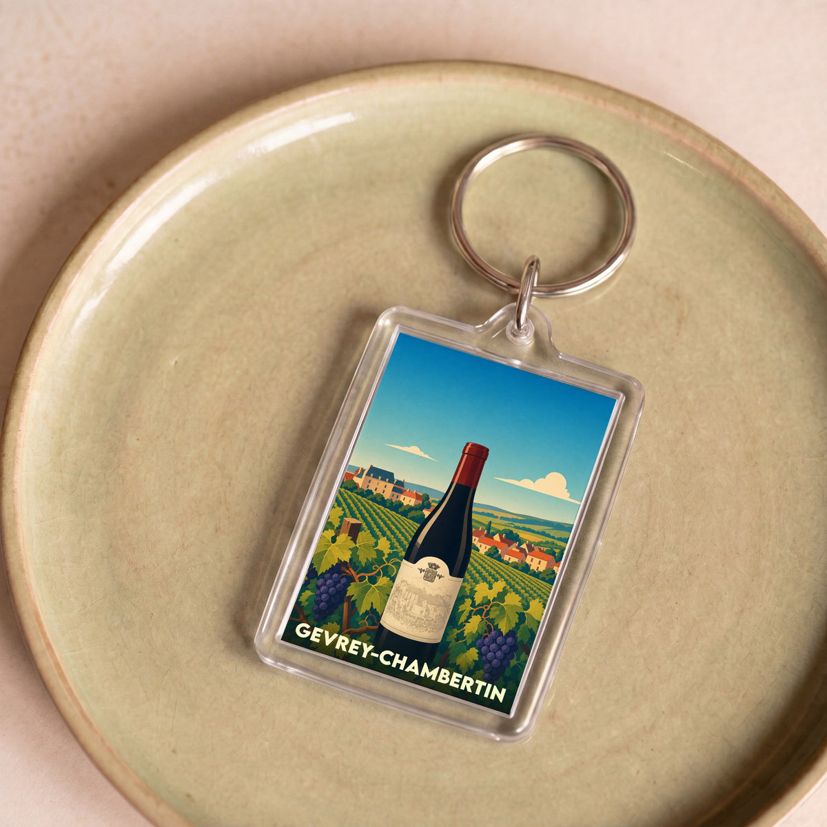 Porte-clés souvenir de la ville de Gevrey-Chambertin avec une illustration stylisée de vignoble et d'une bouteille de vin.