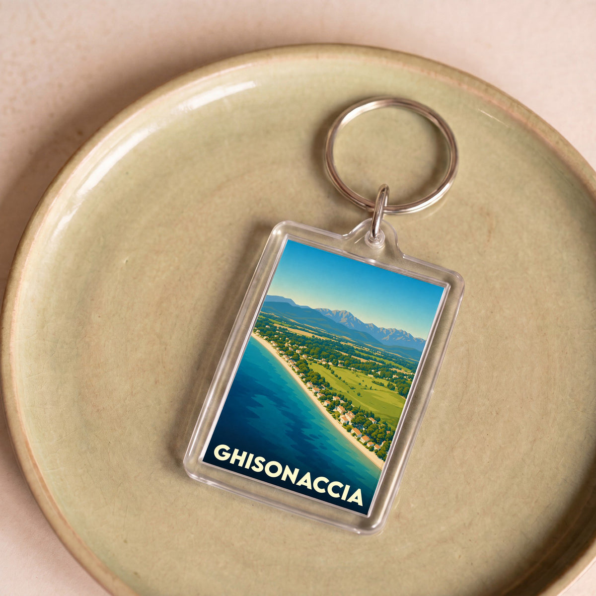 Porte-clés souvenir de la ville de Ghisonaccia avec une illustration stylisée de son littoral et des montagnes.