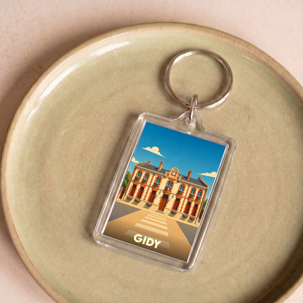 Porte-clés souvenir de la ville de Gidy avec une illustration stylisée de sa mairie.